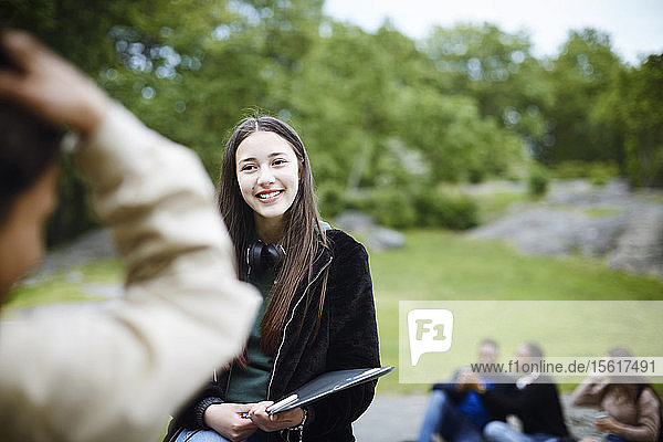 Lächelnder weiblicher Teenager schaut Mann im Park an