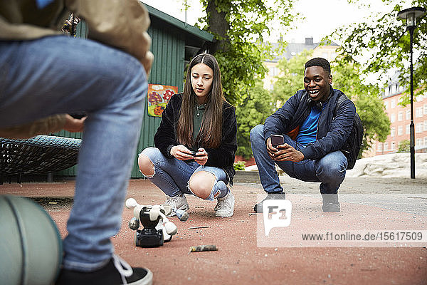 Freunde steuern Roboter mit Smartphone während einer Schlacht im Park