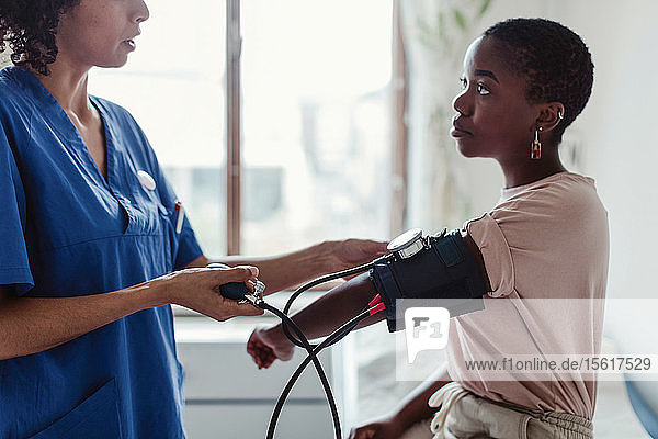 Krankenschwester untersucht den Blutdruck einer jungen Patientin im medizinischen Untersuchungsraum