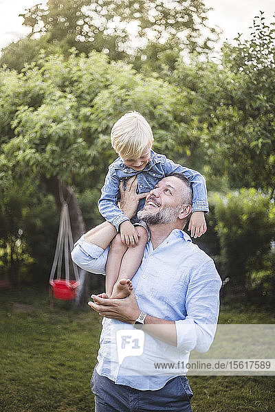 Glücklicher Vater trägt Sohn auf den Schultern im Hinterhof