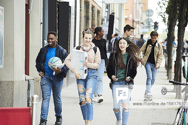 Lächelnde Modefreunde spazieren auf einem Fußweg in der Stadt
