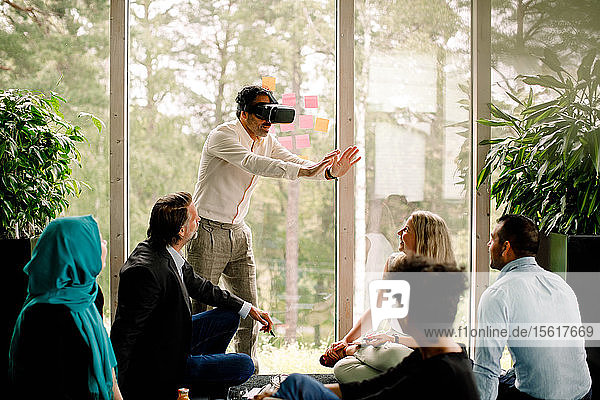 Geschäftsmann trägt einen Virtual-Reality-Simulator während einer Konferenz mit Kollegen im Kongresszentrum
