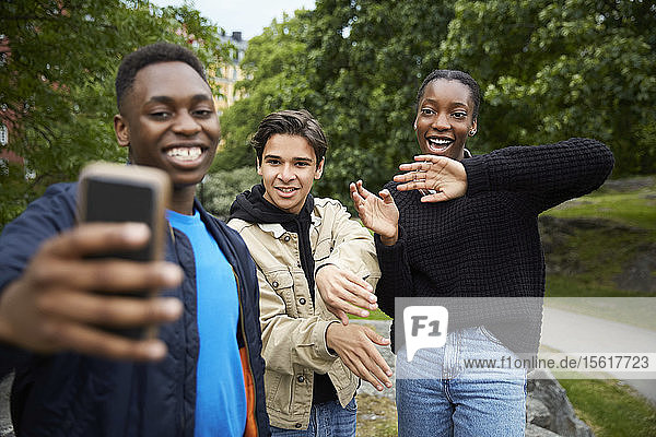 Glückliche Freunde schauen auf Smartphone  während sie im Park Tanz üben