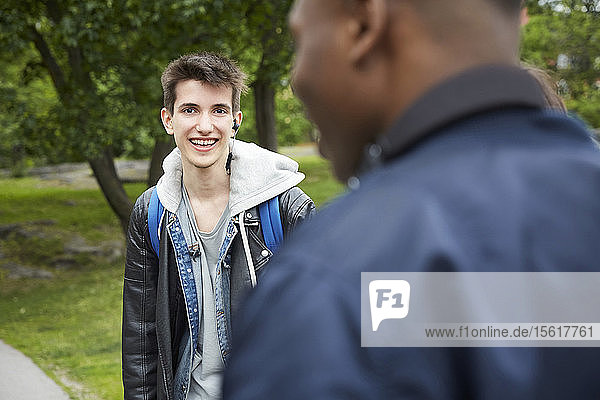 Portrait of smiling teenage boy standing at park