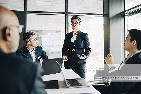 Leitende Geschäftsfrau erklärt Mitarbeitern im Konferenzraum während einer Besprechung im Büro