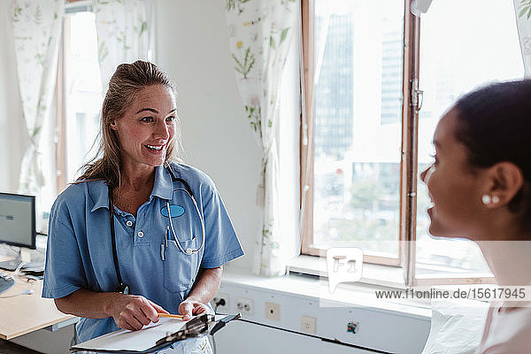 Smiling female nurse talking with patient in hospital