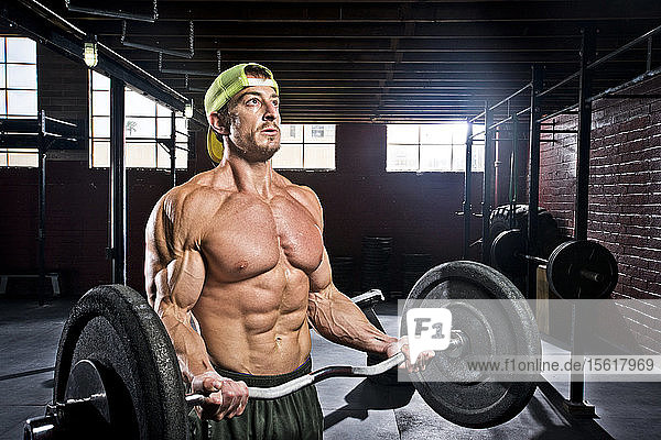 A crossfit athlete performs bicep curls at an old gritty gym in San Diego  CA.