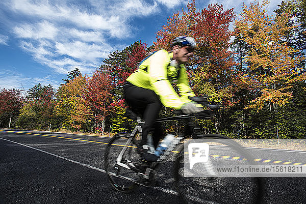 A cyclist speeding along the colorful Kancamagus Highway in New Hampshire.