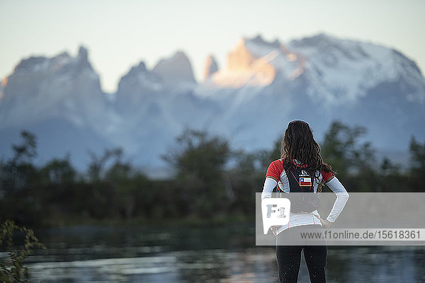 Female trail runner looking at view of mountains near Rio Serrano river in Torres del Paine National Park  Magallanes region  Chile