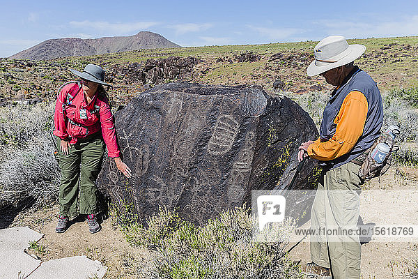 Two tour guides standing beside boulder covered in petroglyphs  Ridgecrest  California  USA