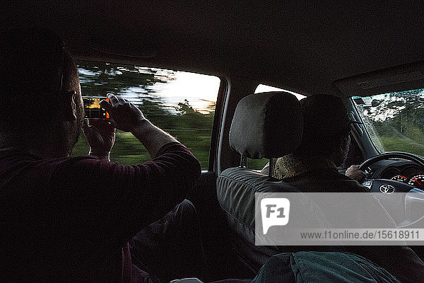 Foto im Auto eines Mannes  der ein Foto mit seinem Smartphone im peruanischen Dschungel macht  Manu-Nationalpark  Peru