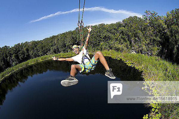 Ein Tourist genießt die Seilrutsche über die Lagune und die Cenoten eines Dorfes in der Nähe von Cob in Quintana Roo  Mexiko