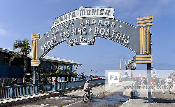 Eingangsbogen zum Santa Monica Pier  vom Pacific Coast Highway aus gesehen. Der Santa Monica Pier ist seit mehr als einem Jahrhundert ein beliebter Ausflugsort und zieht täglich viele Menschen an.