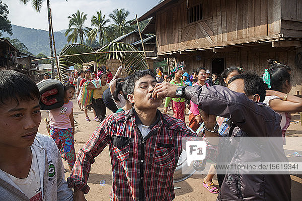 Einem Mann wird bei einer Hochzeitsprozession in Muang Hat Hin  Laos  ein Schuss Lao-lao (Reiswhisky) angeboten.