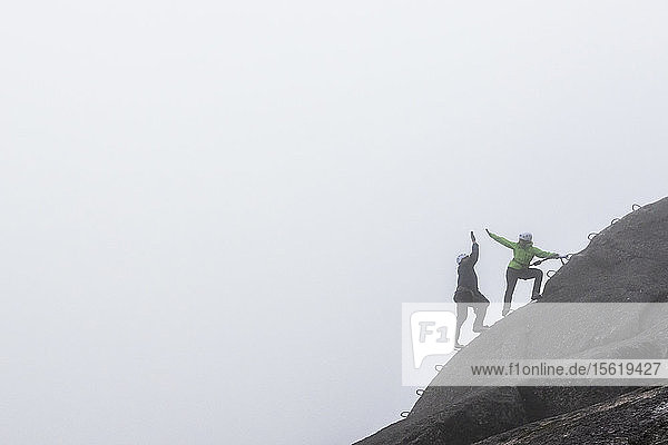 Ein Mann und eine Frau geben sich beim Begehen des Klettersteigs an einem regnerischen Herbsttag in Squamish  British Columbia  die Hand.