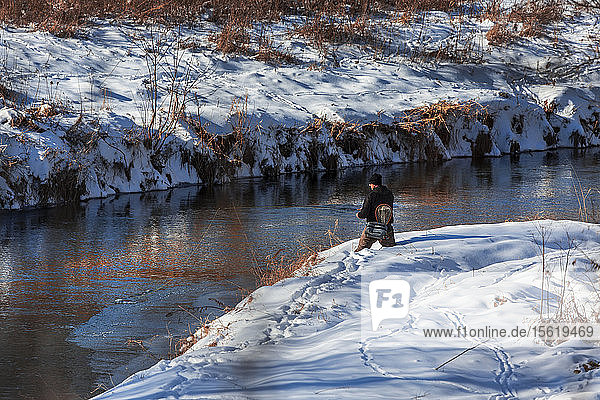 A fly fisherman stands knee deep in fresh snow to cast his line in the Kickapoo River in Wisconsin's Driftless Region.