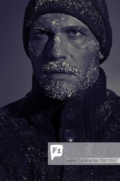 Kreatives Porträt eines Mannes mit eingefrorenem Gesicht und Wollmütze