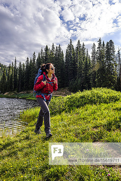 Side view shot of female backpacker hiking on lakeshore  Bolam Pass  Colorado Trail  Colorado  USA