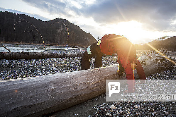 Die professionelle Snowboarderin Helen Schettini macht nach einem langen Tag in Haines  Alaska  Yoga auf einem Baumstamm.
