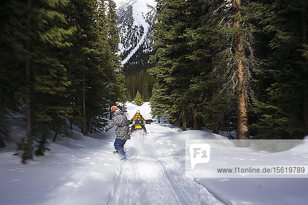 Snowboarder hinter Schneemobil durch Wald geschleppt