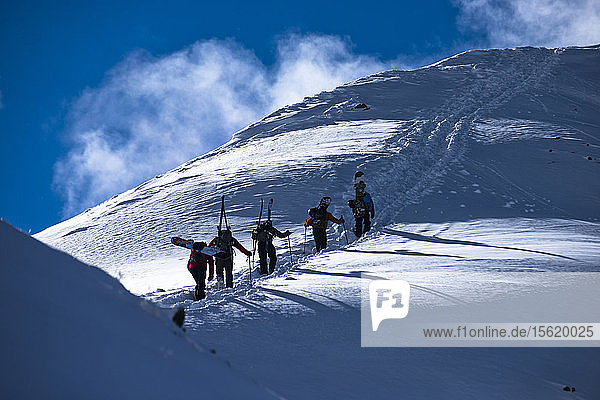 A pack of skiers and snowboarders hike up Silverton Mountain in Colorado.