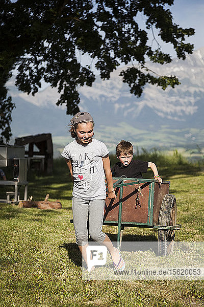 A girl pulls her brother in a cart at Ferme Gabert near Clelles  Is?ï¿½re  France.