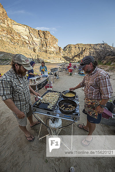 Two men cooking meal in outdoor kitchen during rafting trip  Desolation/Gray Canyon section  Utah  USA