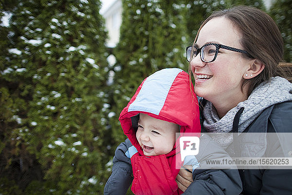 Laughing mother with baby outdoors in winter clothing  Langley  British Columbia  Canada