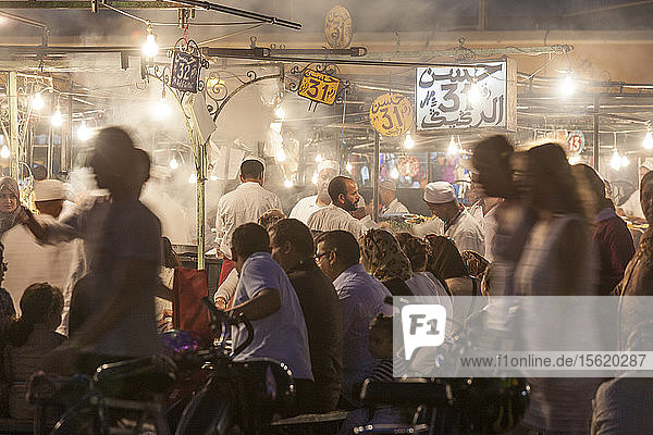 Menschenmassen  die an den Essensständen auf dem Jemaa-EL-Fna-Platz in Marrakesch  Marokko  sitzen und stehen.