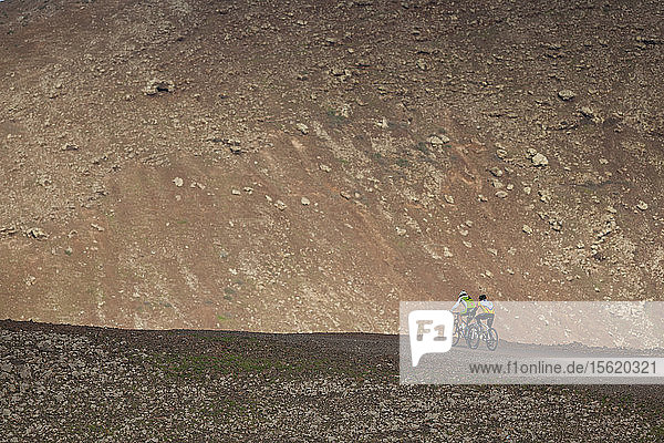 Zwei Personen mit Mountainbike beim Aufstieg auf eine Vulkan-Caldera in Fuerteventura (Kanarische Inseln)