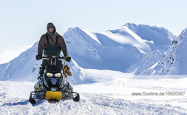 Männlicher Snowboarder  der mit einem Motorschlitten fährt  um Zugang zu erhalten  fährt auf die Kamera zu