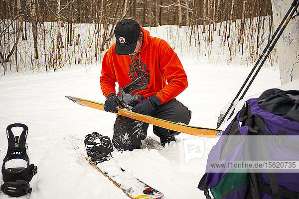 Ein Mann nimmt die Felle von seinem Splitboard im Hinterland von Vermont ab.