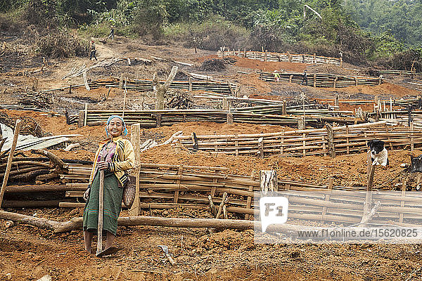 Eine ältere Frau steht am Fuße einer Reihe von Bauplattformen  die von einem Bambusgerüst gehalten werden  an der provisorischen Umsiedlungsstelle oberhalb von Muang Va  Laos. Das Dorf wird durch den Staudamm Nr. 6 des Nam Ou-Flusses vollständig überflutet werden  und die von der Regierung bereitgestellte Umsiedlungsstelle in der Nähe von Hat Sa wird nicht rechtzeitig fertiggestellt werden.
