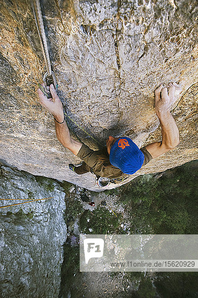 Foto mit Blick von oben auf einen abenteuerlustigen Mann  der den Felsen in der Kletterroute Cyclops (5.13a) in El Portero Chico  Monterrey  Mexiko  erklimmt