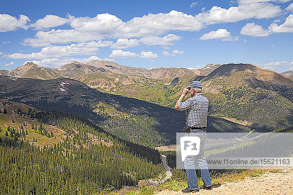Mann schaut durch ein Fernglas auf der Spitze des Loveland Passes