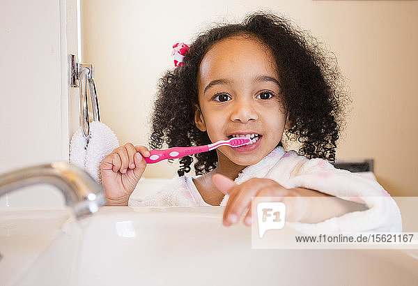 Ein junges  multikulturelles Mädchen putzt sich die Zähne.