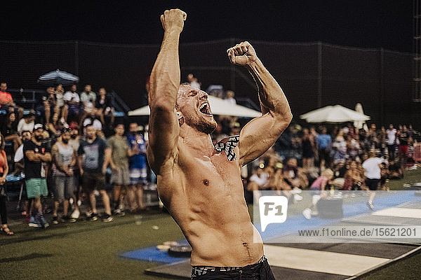 Taillenaufnahme eines Crossfit-Sportlers ohne Hemd  der seinen Sieg feiert