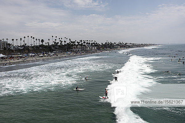 Surfers catch a party wave after taking part in a paddle out honoring local surfing legend known as Skydog at Oceanside Beach in Oceanside  Calif.  on August 3  2014.