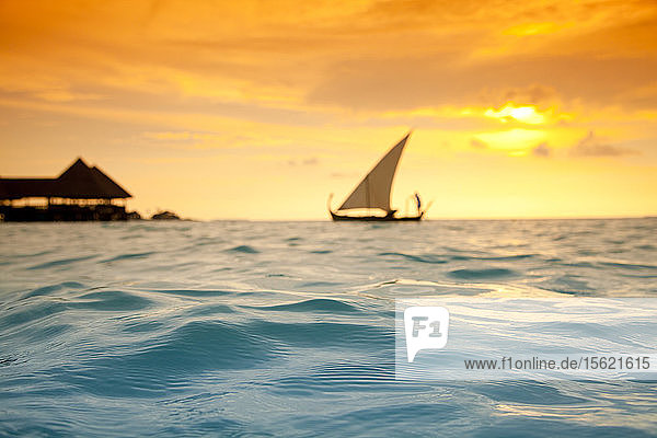 Traditionelles maledivisches Segelboot im Meer bei Sonnenuntergang