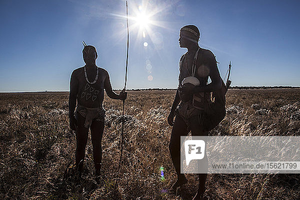 Photograph of two members of San people walking through underbrush in Kalahari Desert  Botswana