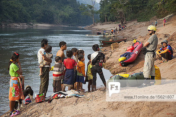 Robert Hahn (front) and Mung attract a large audience of curious locals on the shore of the Nam Ou River in Ban Phu Muang  Laos.