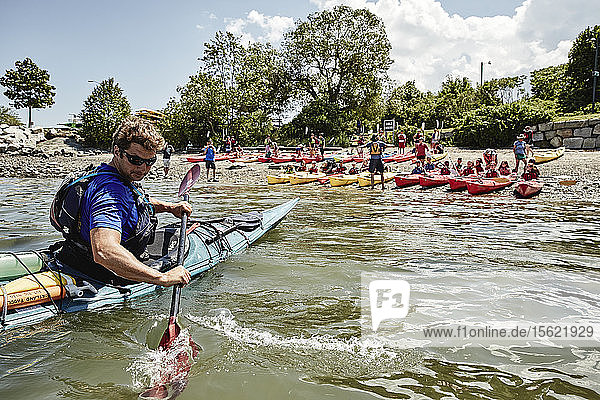Kayaking instructor paddling in front of students sitting in kayaks  Portland  Maine  USA