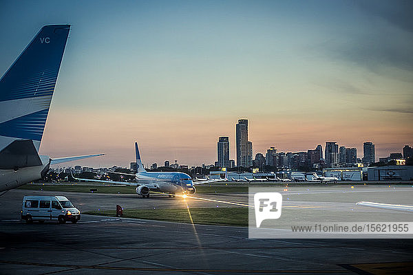 View of airplane at airport runway at sunset and skyline of Buenos Aires  Argentina