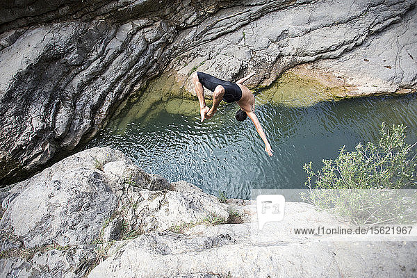 Ein junger Mann macht einen Rückwärtssalto in einen natürlichen Pool in Montanejos (Spanien).