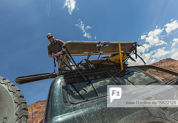 Low Angle View Of Man Unloading Gear From The Top Of Vehicle