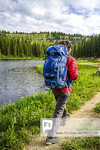 Rear view shot of female backpacker hiking on lakeshore Bolam Pass Colorado Trail Colorado USA