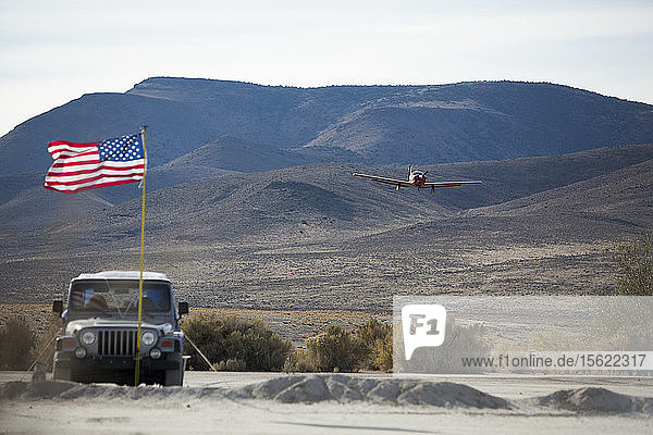 Flugzeug im Landeanflug mit Geländewagen im Vordergrund in der ländlichen Wüste Nevadas beim High Sierra Fly In