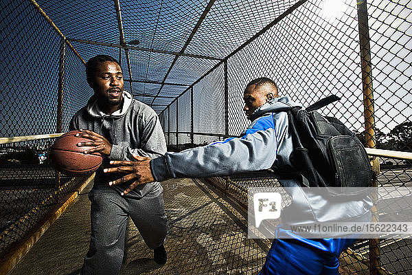 Two young guys messing around with a basketball on a footbridge in San Diego  CA.