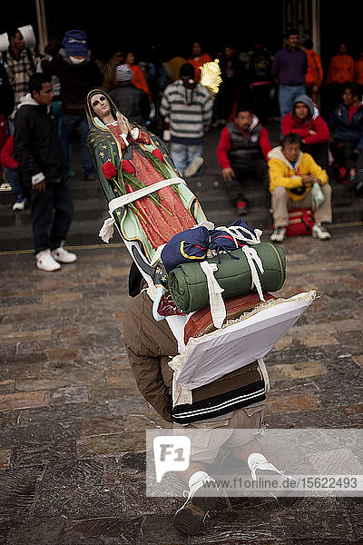 Ein Pilger trägt ein Bild der Jungfrau von Guadalupe während der jährlichen Wallfahrt zur Basilika Unserer Lieben Frau von Guadalupe auf dem Tepeyac-Hügel in Mexiko-Stadt  Mexiko. Guadalupe ist bei den Eingeborenen als Tonantzin bekannt  was in der mexikanischen Sprache Nahuatl Unsere Mutter bedeutet. Jedes Jahr kommen Millionen von Menschen zu dieser Wallfahrt.
