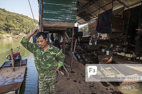Vietnamesische Männer bedienen eine mechanische Goldbaggeranlage  die auf dem Nam Ou Fluss in Laos schwimmt. Sechs Männer leben monatelang auf dem Schiff  rotieren den ganzen Tag über und arbeiten paarweise  um die Maschine ständig in Betrieb zu halten.